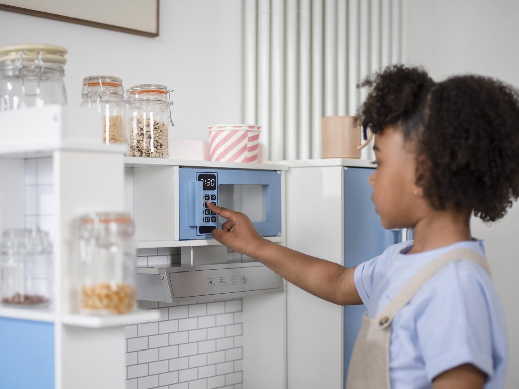 Child pretending to set the microwave on the Plum Penne Pantry Wooden Corner Kitchen and Fridge
