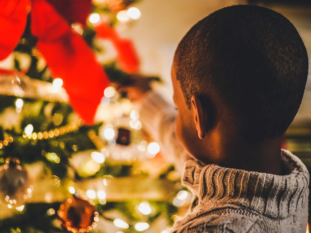 Child putting decoration on Christmas Tree