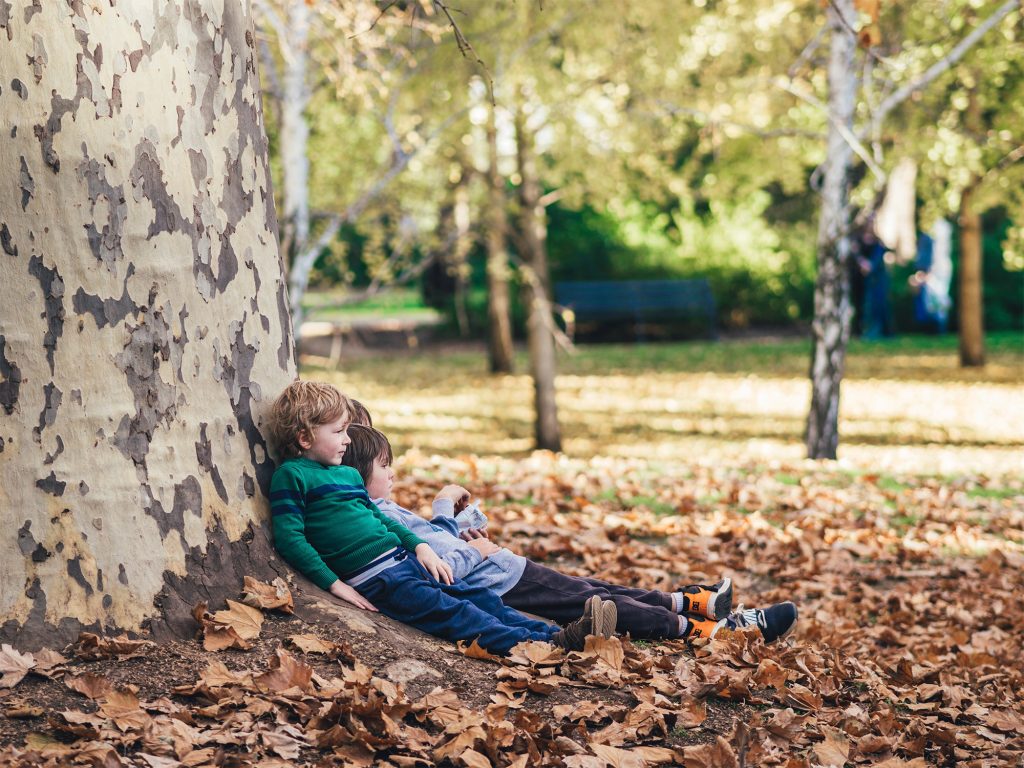 Children sitting against tree in autumn 