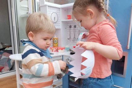 children in play kitchen with paper crown