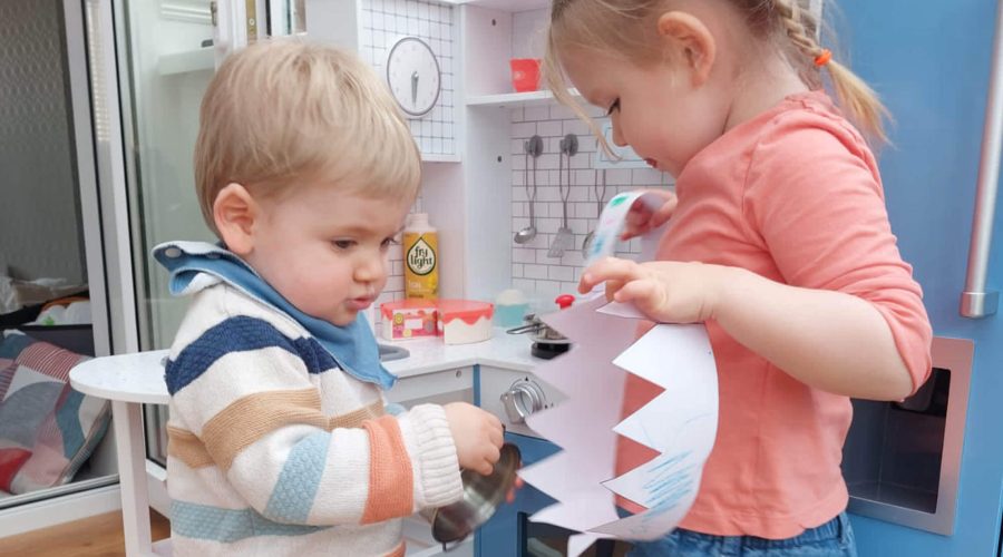 children in play kitchen with paper crown