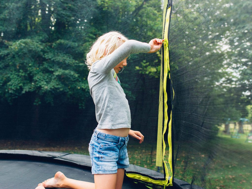 Girl zipping up trampoline enclosure 
